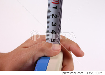 Boy's hands playing with a tape measure Boy's hands playing with a tape measure 135437174