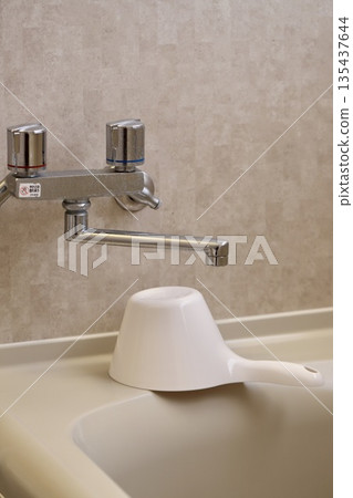 The two-handle mixer tap and hand bucket in the bathroom are not well-cleaned. 135437644