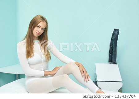 Young caucasian female in white outfit relaxing on spa bed in modern wellness 135437704