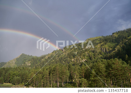 Double rainbow over lush green forest and mountain landscape in daylight Double rainbow over lush green forest and mountain landscape in daylight 135437718