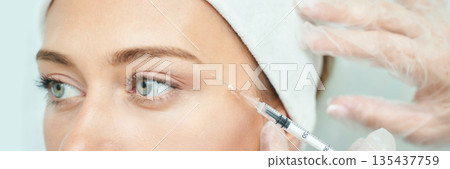 Young caucasian female receiving cosmetic injection at spa with close-up 135437759