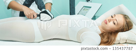 Young caucasian female undergoing body contouring treatment with modern beauty 135437787