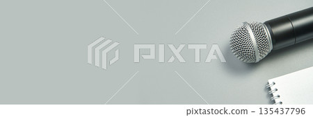 Microphone and open notebook on gray background for music, speech, or podcast Microphone and open notebook on gray background for music, speech, or podcast 135437796