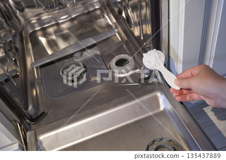 Hand adding detergent into open dishwasher with stainless steel interior Hand adding detergent into open dishwasher with stainless steel interior 135437889