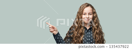 Smiling caucasian young girl with long wavy hair pointing right Smiling caucasian young girl with long wavy hair pointing right 135437922