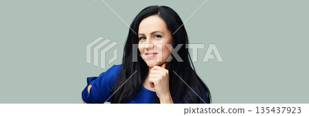 Confident caucasian female adult with long black hair in blue shirt against Confident caucasian female adult with long black hair in blue shirt against 135437923