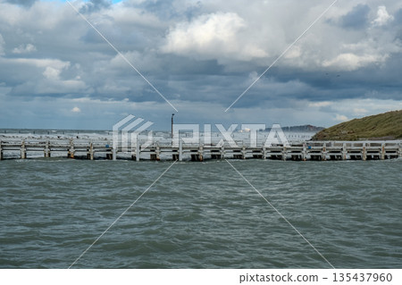 ocean facing stormy skies and structures, waves crash against pier beneath looming stormy sky ocean facing stormy skies and structures, waves crash against pier beneath looming stormy sky 135437960