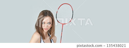 Caucasian female young adult holding badminton racket against gray background 135438021