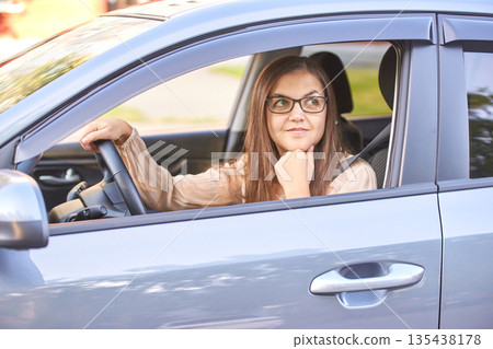 Young caucasian woman driving car with smile while looking out window 135438178