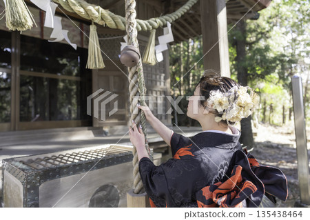 A woman in a kimono praying at a shrine A woman in a kimono praying at a shrine 135438464