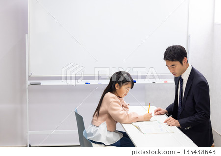 一位小學生正在接受補習班老師的輔導。 135438643