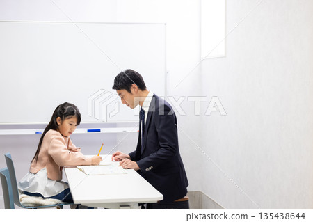 An elementary school girl being taught by a cram school teacher An elementary school girl being taught by a cram school teacher 135438644