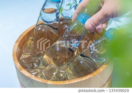 Summertime, picking up a glass bottle of Ramune with marbles in an ice-cold wooden tub Summertime, picking up a glass bottle of Ramune with marbles in an ice-cold wooden tub 135439029