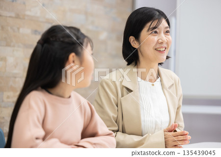 一位身穿西裝的母親正在和一名小學生說話。 一位身穿西裝的母親正在和一名小學生說話。 135439045