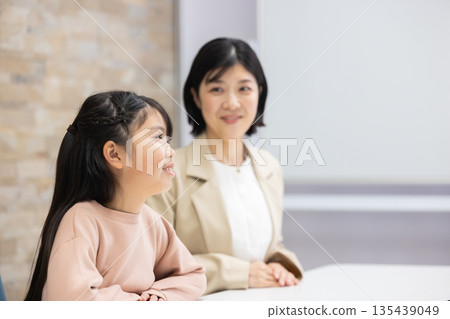 一位身穿西裝的母親正在和一名小學生說話。 135439049