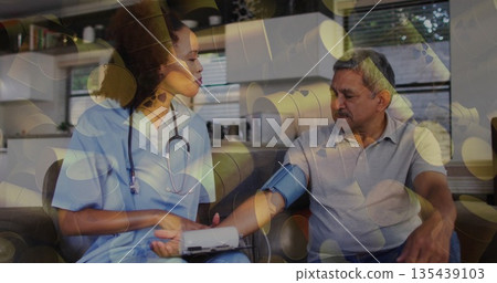 Wrapping blood pressure cuff around patient's arm, nurse wearing scrubs reading monitor at home Wrapping blood pressure cuff around patient's arm, nurse wearing scrubs reading monitor at home 135439103
