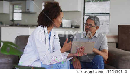 Doctor in scrubs with lab coat consulting patient in home kitchen area, with tablet and stethoscope Doctor in scrubs with lab coat consulting patient in home kitchen area, with tablet and stethoscope 135439140