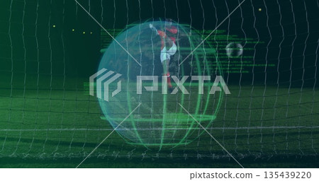 Leaping goalkeeper in red kit diving toward soccer ball in stadium net, with digital grid overlay 135439220