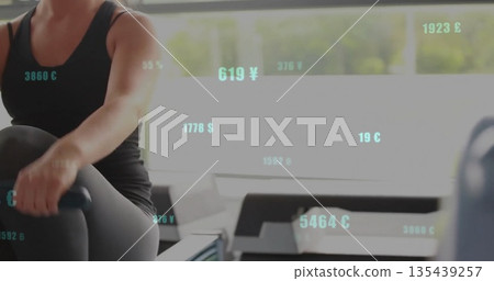 Woman in black sportswear using rowing machine at gym, with windows, currency overlays, copy space Woman in black sportswear using rowing machine at gym, with windows, currency overlays, copy space 135439257