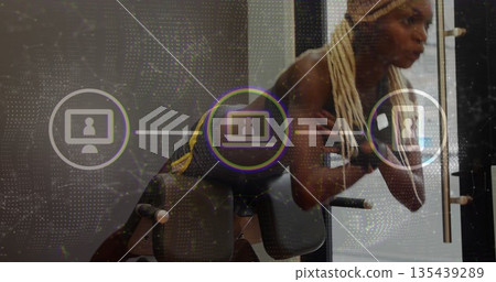 Athlete performing back extension on bench in gym wearing sports bra, leggings with digital overlay 135439289