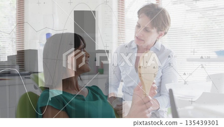 Holding mirror, woman patient comparing shade guide with clinician in dental chair, copy space Holding mirror, woman patient comparing shade guide with clinician in dental chair, copy space 135439301
