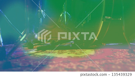 Pressing tan lace-up boot on bass drum pedal on stage, with patterned rug and colored lighting 135439329