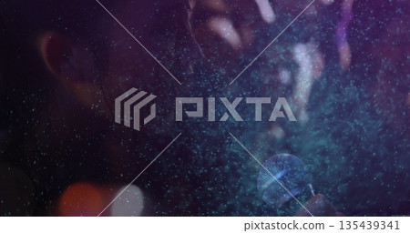 Singing female singer holding microphone near mouth on concert stage, with mist and stage lights 135439341