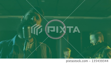 Bearded singer in denim jacket singing into vintage microphone in studio, guitars drums, copy space Bearded singer in denim jacket singing into vintage microphone in studio, guitars drums, copy space 135439344
