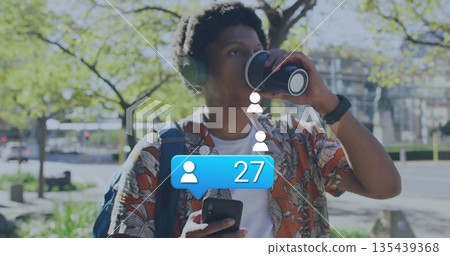 Sipping coffee man in floral shirt and headphones checking phone at park with social media icons Sipping coffee man in floral shirt and headphones checking phone at park with social media icons 135439368