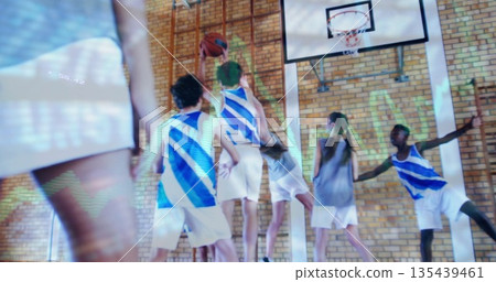 Jumping teenage boy in blue-and-white jersey grabbing basketball in gym, with hoop and backboard Jumping teenage boy in blue-and-white jersey grabbing basketball in gym, with hoop and backboard 135439461