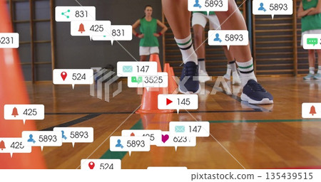 Navigating athlete in green uniform performing agility drill in gym, with orange cones, media icons 135439515