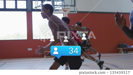 Sprinting Hispanic man in grey shirt leading drill on basketball court, with hoop, lines and bench 135439517