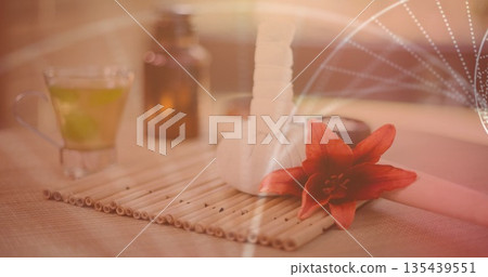 Displaying herbal compress ball paired with red lily flower on bamboo mat at spa, amber bottle 135439551