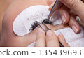 Close up of individual artificial Eyelash Extensions being applied at Beauty Salon 135439693