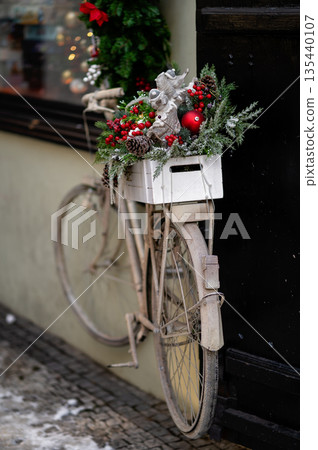 Vintage bicycle decorated with Christmas greenery and ornaments against a dark wall Vintage bicycle decorated with Christmas greenery and ornaments against a dark wall 135440107