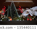 Festive holiday planter with miniature trees, red ornaments, and decorative silver foliage 135440111