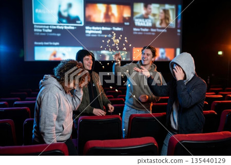Group of friends enjoying popcorn in a movie theater with vibrant atmosphere and excitement 135440129