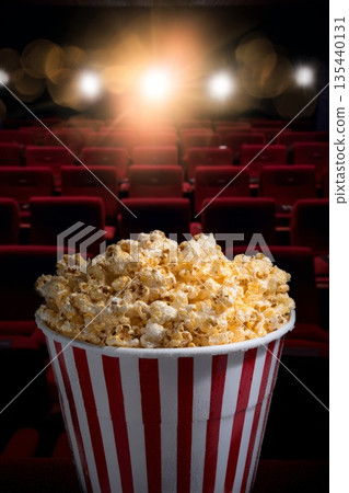 Freshly popped popcorn in a striped bucket, illuminated by theater lights, ready for movie enjoyment 135440131