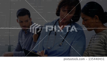 Writing white female doctor in blue scrubs on clipboard in medical exam room, with stethoscope Writing white female doctor in blue scrubs on clipboard in medical exam room, with stethoscope 135440431