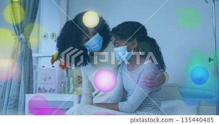 Comforting mother wrapping arm around daughter on hospital bed near IV stand, with surgical masks Comforting mother wrapping arm around daughter on hospital bed near IV stand, with surgical masks 135440485