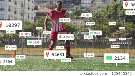 Controlling player in red-white jersey dribbling ball on turf with orange cone and digital icons 135440543