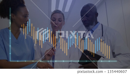 Analyzing medical team pointing at graph overlay in hospital corridor holding tablet, stethoscope 135440607