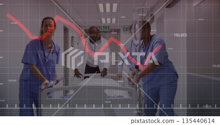 Medical team pushing empty gurney in hospital corridor, in scrubs with stethoscopes and exit signs 135440614