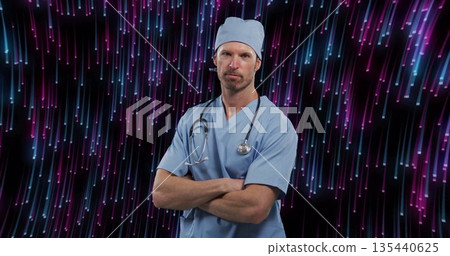 Standing doctor wearing blue scrubs and scrub cap in studio, with stethoscope and LED streaks Standing doctor wearing blue scrubs and scrub cap in studio, with stethoscope and LED streaks 135440625