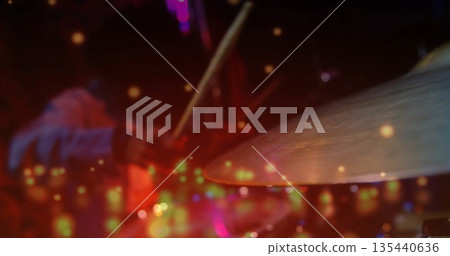 Indian drummer wearing shirt hitting cymbal with drumstick on dimly lit stage, under stage lights 135440636