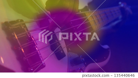 Plucking musician's gloved hand fretting strings on bass guitar on stage, with metal bridge pickups Plucking musician's gloved hand fretting strings on bass guitar on stage, with metal bridge pickups 135440646