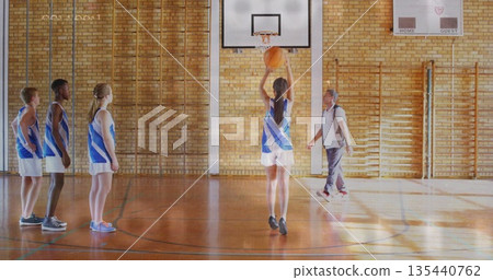 Teenage basketball player in uniform taking free throws in school gym, with basketball hoop Teenage basketball player in uniform taking free throws in school gym, with basketball hoop 135440762