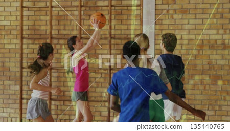 Girl wearing pink top, gray shorts shooting basketball in school gym, with hoop and climbing bars Girl wearing pink top, gray shorts shooting basketball in school gym, with hoop and climbing bars 135440765