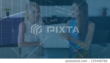 Two businesswomen examining document folder and reviewing financial overlays at office glass table Two businesswomen examining document folder and reviewing financial overlays at office glass table 135440780