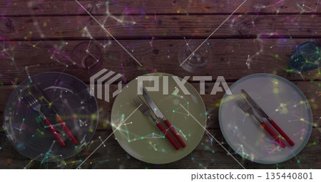 Showing three round plates with red-handled cutlery and glasses on wooden table, network overlay Showing three round plates with red-handled cutlery and glasses on wooden table, network overlay 135440801